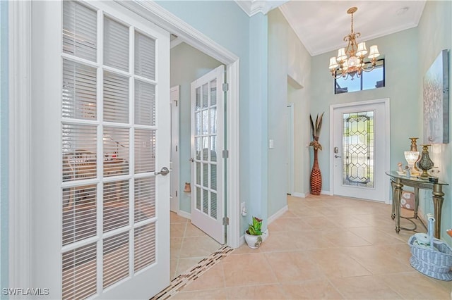 entryway featuring light tile patterned floors, baseboards, a chandelier, and crown molding