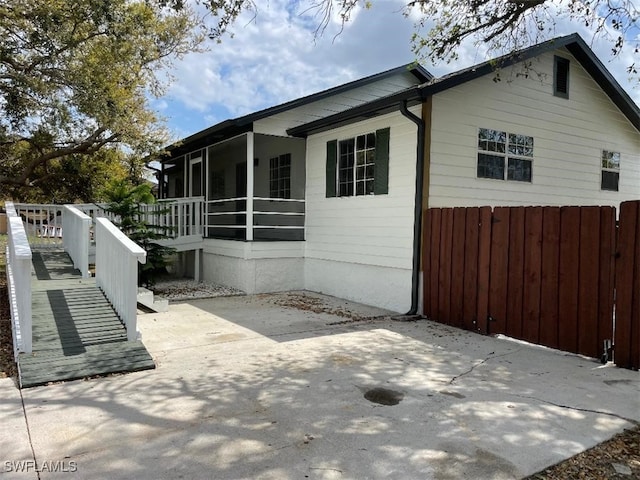 view of property exterior with a patio area and a sunroom