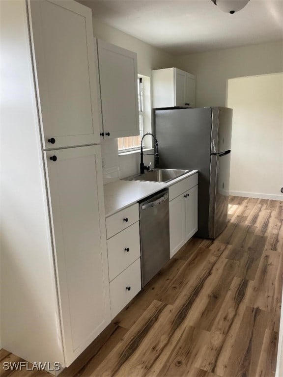 kitchen featuring a sink, white cabinetry, light countertops, light wood-type flooring, and dishwasher