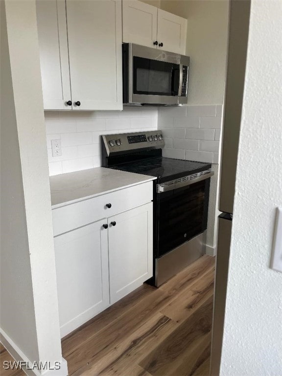 kitchen featuring appliances with stainless steel finishes, dark wood-type flooring, decorative backsplash, and white cabinetry