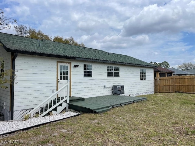 rear view of property featuring a yard, cooling unit, and fence