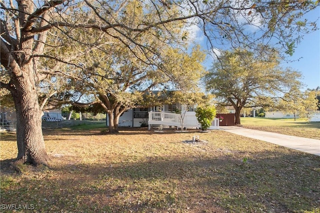 obstructed view of property with driveway, covered porch, and a front yard