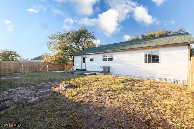 back of property with central AC unit, a lawn, and a fenced backyard