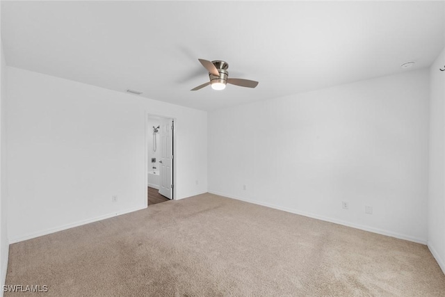 carpeted spare room featuring visible vents, ceiling fan, and baseboards