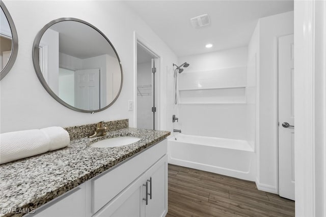 full bath with visible vents, wood finished floors, recessed lighting, washtub / shower combination, and vanity