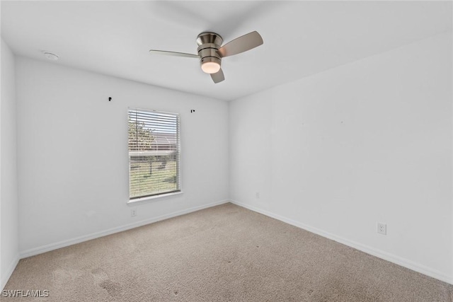 carpeted spare room with a ceiling fan and baseboards