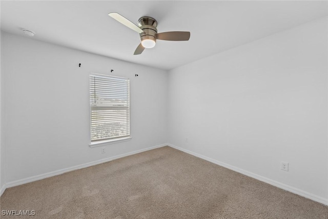 spare room with carpet flooring, baseboards, and ceiling fan