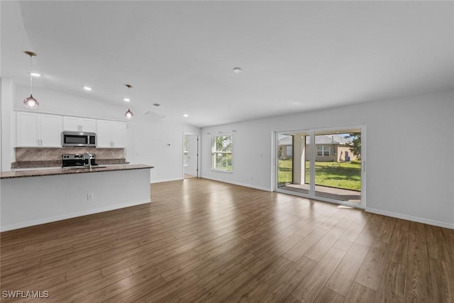 unfurnished living room with dark wood finished floors, vaulted ceiling, recessed lighting, and baseboards