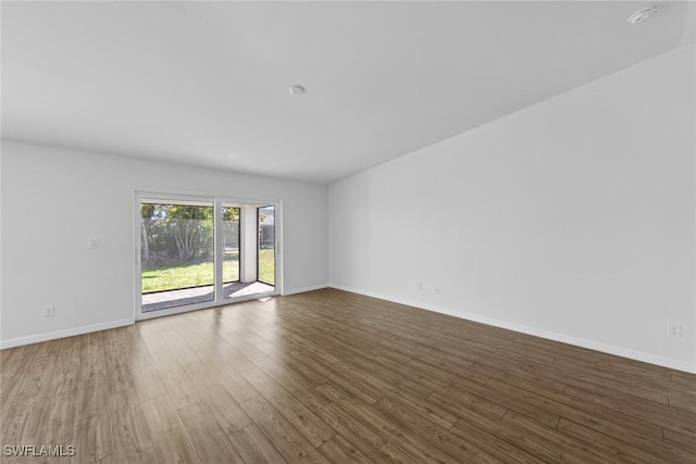 spare room with baseboards and wood finished floors