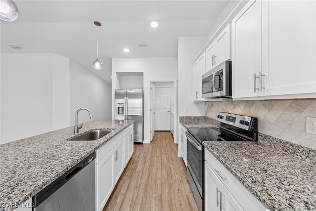 kitchen featuring a sink, stainless steel appliances, white cabinetry, tasteful backsplash, and light wood-type flooring