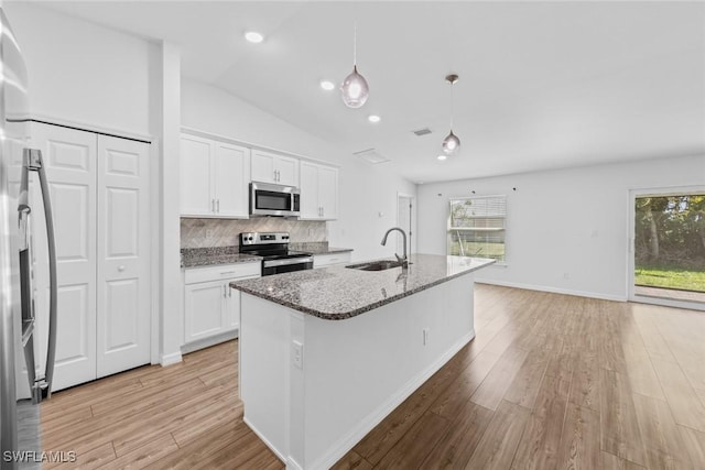 kitchen featuring appliances with stainless steel finishes, stone countertops, light wood-style floors, and a sink