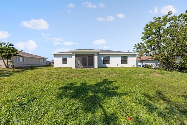 back of property with stucco siding, a lawn, and fence