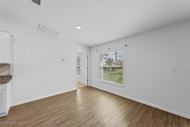 interior space featuring visible vents, baseboards, attic access, and light wood finished floors