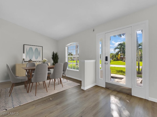 dining room with vaulted ceiling, wood finished floors, and baseboards