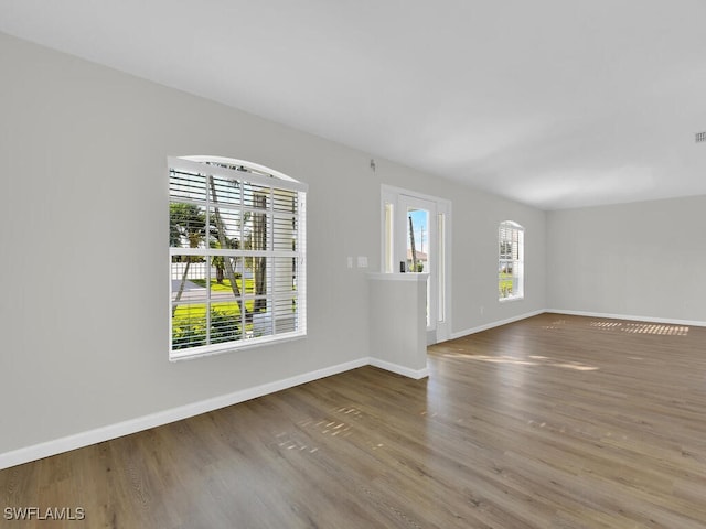 unfurnished room with a wealth of natural light, baseboards, and wood finished floors