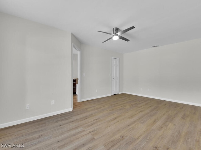 spare room with a ceiling fan, wood finished floors, visible vents, and baseboards