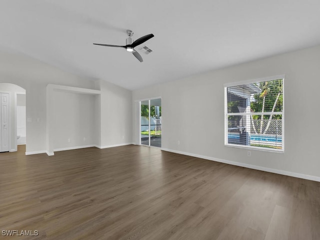 unfurnished living room with visible vents, arched walkways, ceiling fan, wood finished floors, and vaulted ceiling