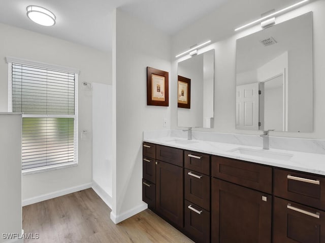 bathroom featuring visible vents, a sink, baseboards, and wood finished floors