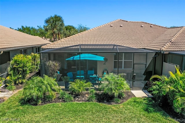 back of house featuring a lanai, a tiled roof, a yard, and a patio