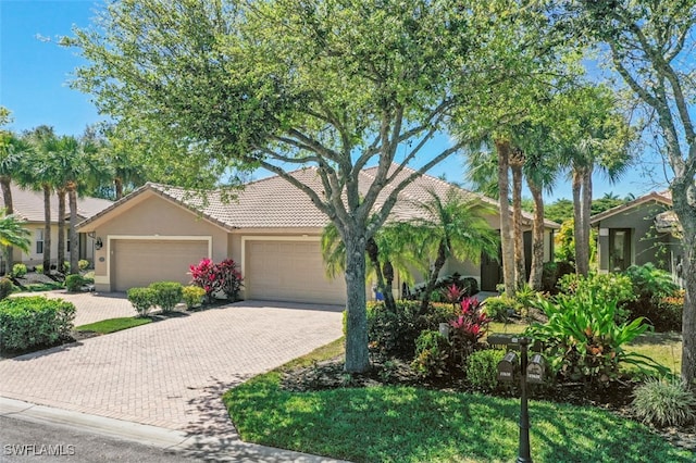 view of front of home with a tiled roof, stucco siding, an attached garage, and decorative driveway