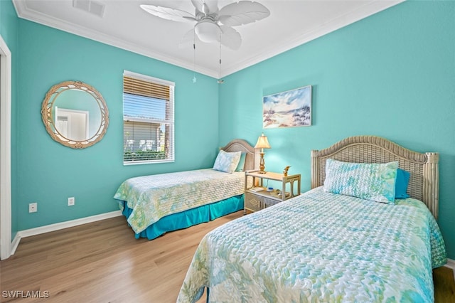 bedroom with wood finished floors, baseboards, visible vents, ceiling fan, and ornamental molding