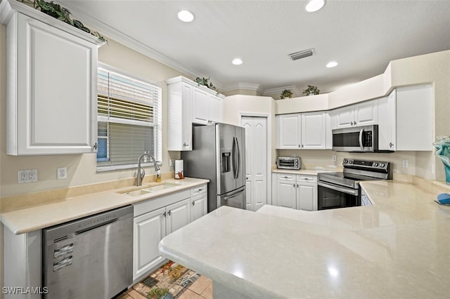 kitchen with visible vents, ornamental molding, a sink, a peninsula, and appliances with stainless steel finishes