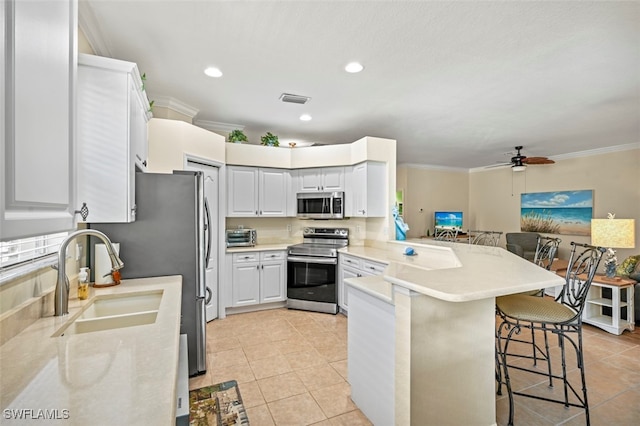 kitchen with visible vents, a kitchen bar, a peninsula, stainless steel appliances, and a sink