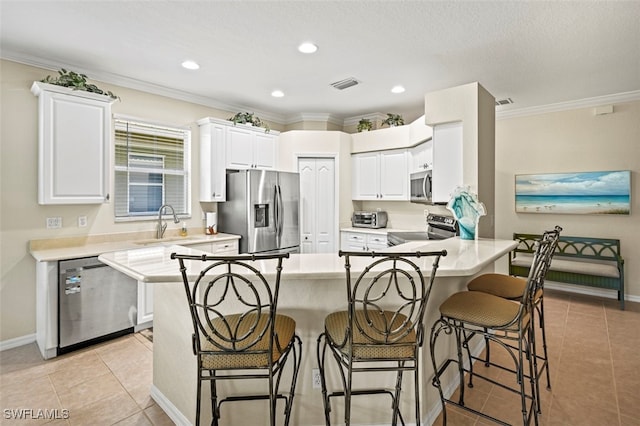 kitchen featuring visible vents, appliances with stainless steel finishes, a peninsula, light tile patterned flooring, and crown molding