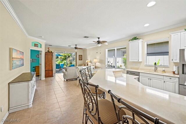 kitchen featuring ornamental molding, appliances with stainless steel finishes, a kitchen bar, and a sink