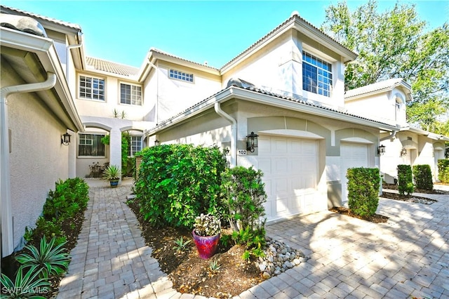 view of front of home featuring a tile roof, decorative driveway, a garage, and stucco siding