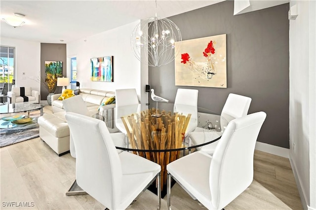 dining room featuring a chandelier, baseboards, and wood finished floors