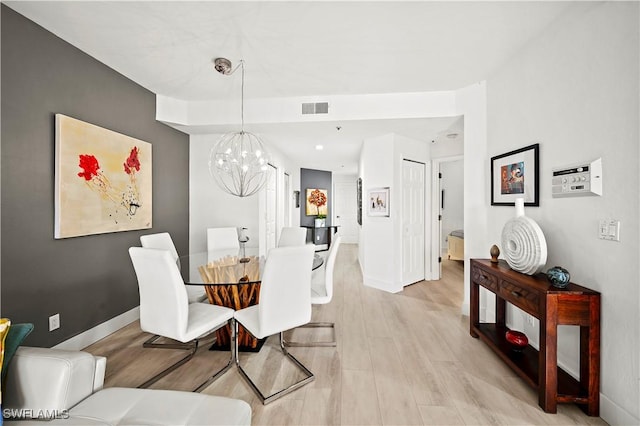 dining area with baseboards, visible vents, a notable chandelier, and light wood-type flooring