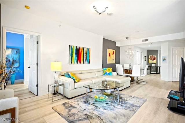 living area with visible vents, baseboards, an inviting chandelier, and light wood finished floors