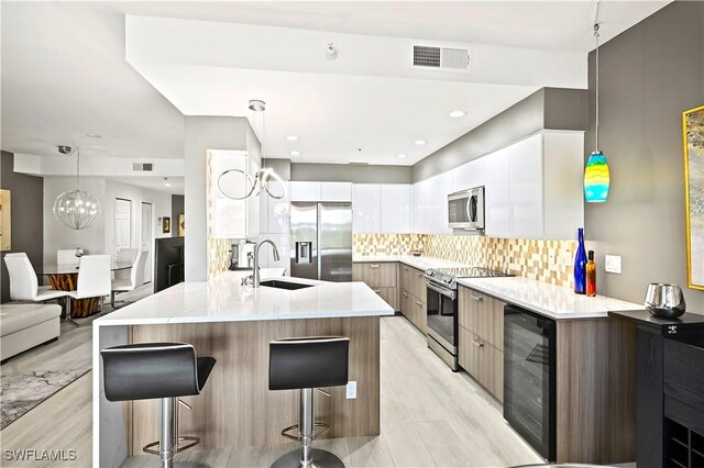 27091 Lake Harbor Ct Unit 102, Bonita Springs, FL 34134 - kitchen featuring appliances with stainless steel finishes, wine cooler, a sink, modern cabinets, and a kitchen breakfast bar