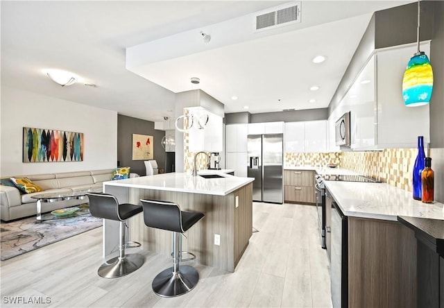 kitchen with visible vents, a kitchen breakfast bar, stainless steel appliances, modern cabinets, and a sink