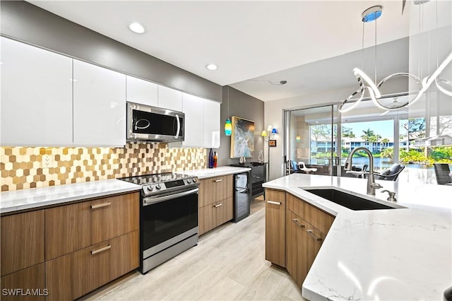 kitchen featuring a sink, modern cabinets, appliances with stainless steel finishes, and white cabinets