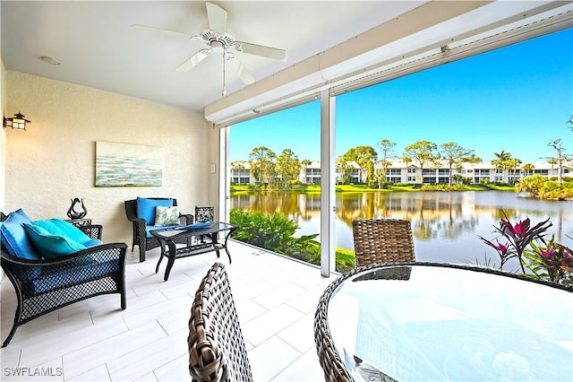 sunroom with ceiling fan and a water view