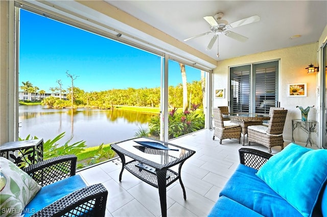 sunroom / solarium with a ceiling fan and a water view