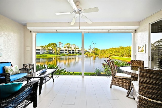 sunroom featuring a ceiling fan and a water view