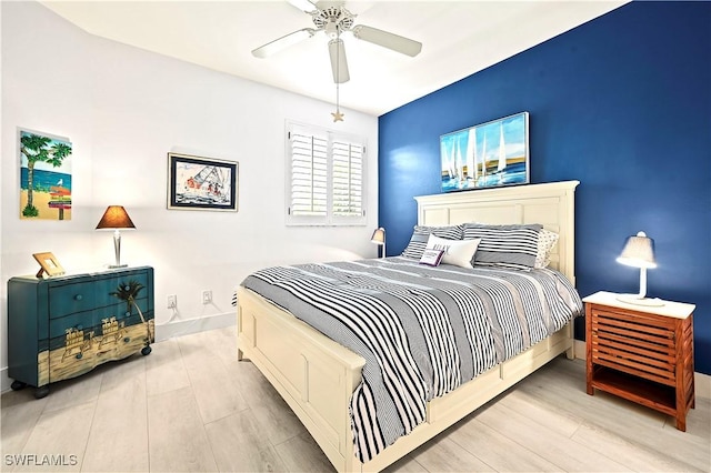 bedroom featuring baseboards, wood finished floors, and a ceiling fan