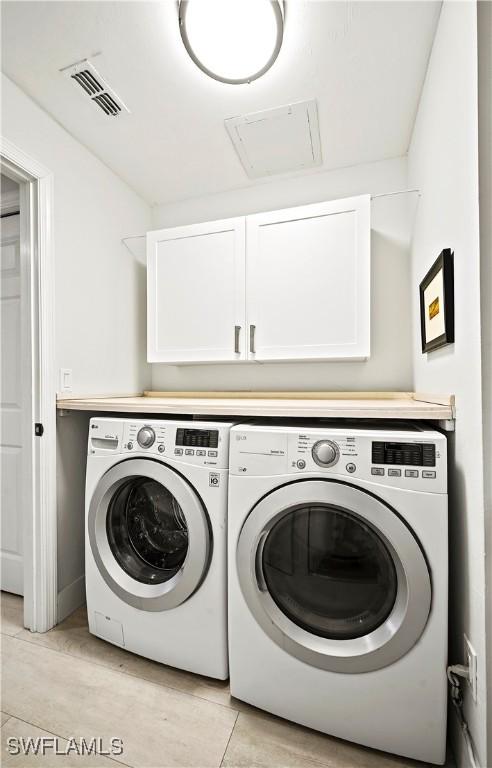 clothes washing area featuring cabinet space, washing machine and dryer, and visible vents