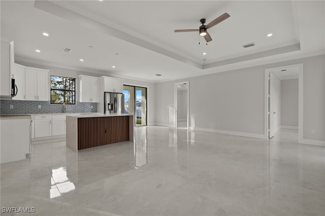 kitchen with open floor plan, a tray ceiling, stainless steel refrigerator with ice dispenser, and a kitchen island