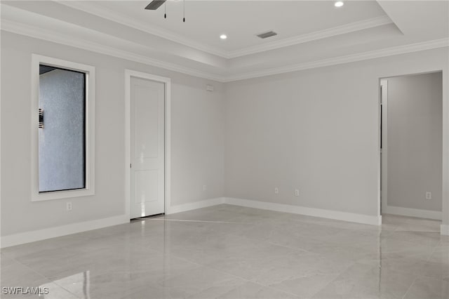 empty room featuring a tray ceiling, baseboards, visible vents, and crown molding