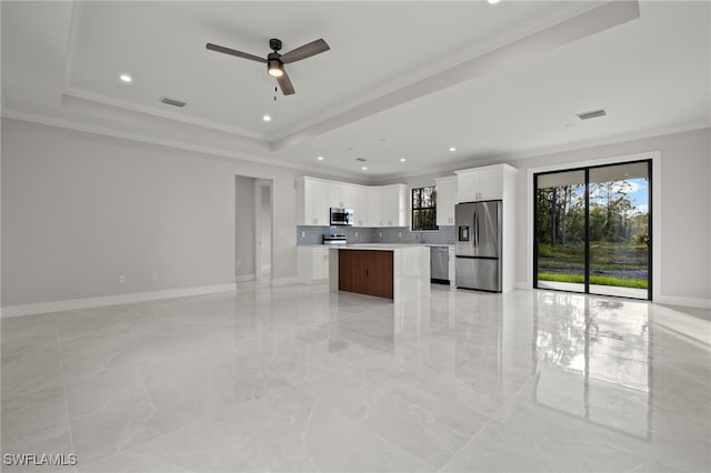 kitchen with a center island, a tray ceiling, stainless steel appliances, visible vents, and open floor plan