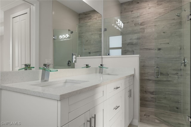 bathroom featuring double vanity, a stall shower, and a sink