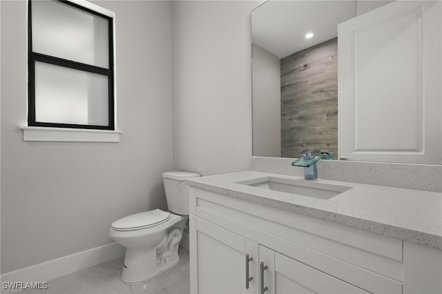 bathroom featuring baseboards, vanity, and toilet