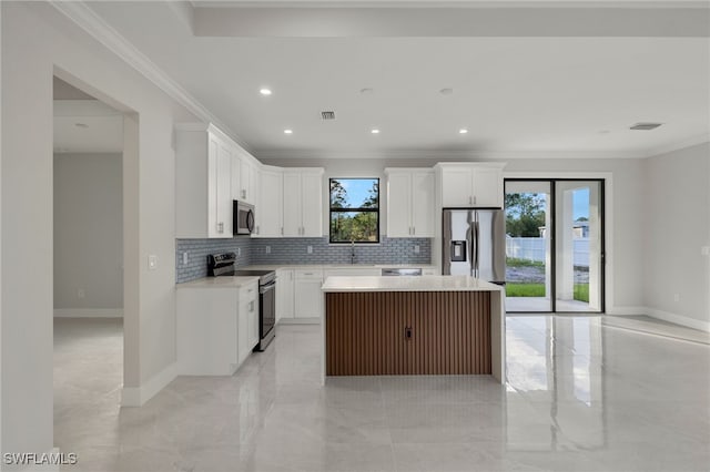 kitchen featuring ornamental molding, appliances with stainless steel finishes, a center island, and decorative backsplash