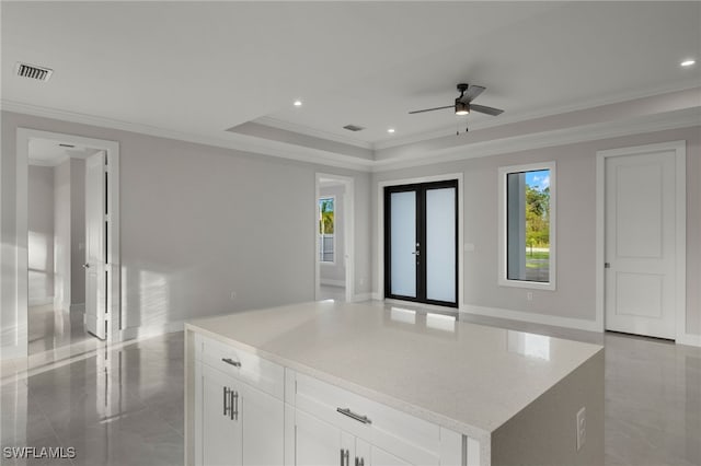 kitchen with marble finish floor, a raised ceiling, visible vents, ornamental molding, and white cabinets