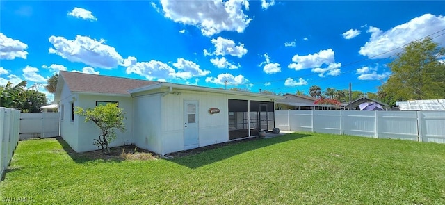 rear view of house with a lawn, a fenced backyard, and a sunroom