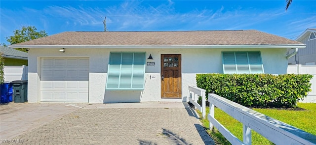 ranch-style house featuring concrete driveway, fence, roof with shingles, and stucco siding